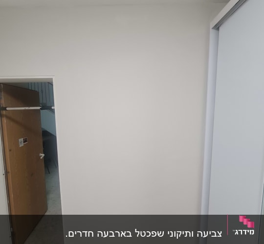 קיר צבוע בלבן עם דלת פתוחה בצד